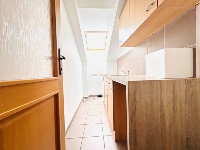 KANCELÁRSKE PRIESTORY- 120m2- KOMÁROVSKÁ - Úzka kuchynská časť v kancelárii s oknom a podlahou s dreveným dekorom.