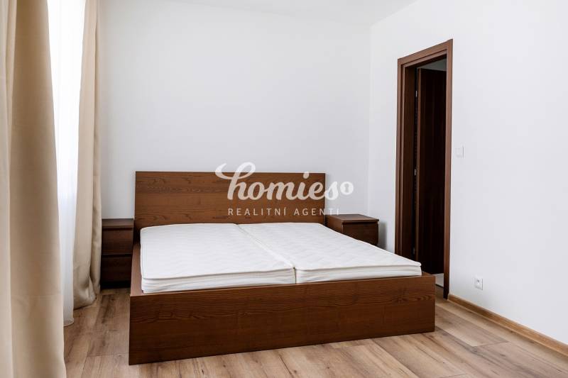 PRENÁJOM 3 izbový luxusný byt  v centre Nitry s veľkou terasou - Spálňa v 3-izbovom byte s posteľou z tmavého dreva a podlahou s dreveným dekorom.