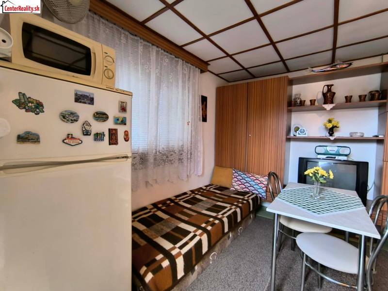 ‼️BRODZANY - ZÁHRADA S MUROVANOU CHATKOU NA PREDAJ, okr. PARTIZÁNSKE‼️ - Malá kuchyňa na chate s ladením do dreveného dekoru, jedálenským stolom a chladničkou.