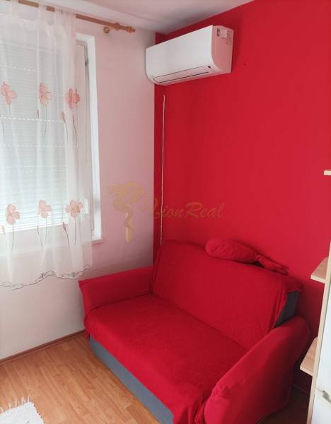 1-izb. byt, Pezinok - Sever, ul. Suvorovova - Červená pohovka, stenová klimatizácia a záclona v 1-izbovom byte s podlahou s dreveným dekorom.