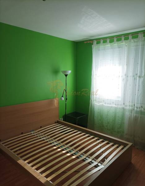 1-izb. byt, Pezinok - Sever, ul. Suvorovova - Spálňa v 1-izbovom byte s posteľou, zelenými stenami a podlahou s dreveným dekorom.