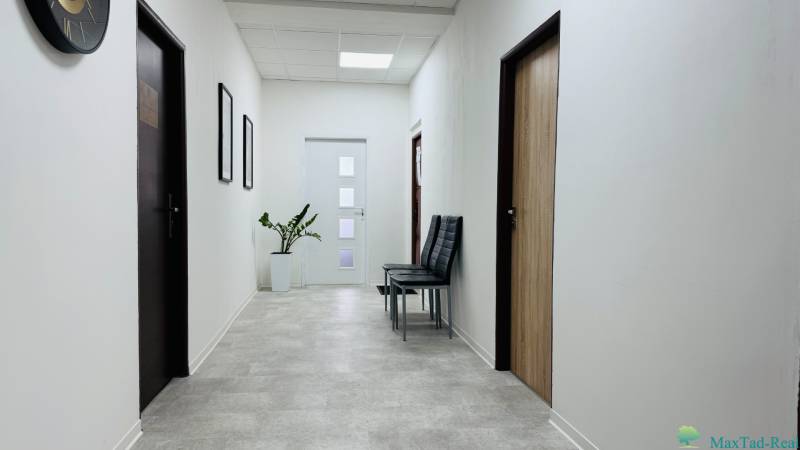Kancelária s výhľadom na centrum Michaloviec. 16 m2 - Chodba v Kancelárie s bielymi stenami, rastlinou, stoličkami a dverami s dreveným dekorom.