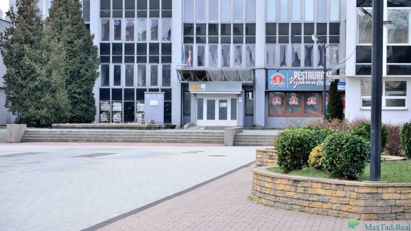 Kancelária s výhľadom na centrum Michaloviec. 16 m2 - Budova s kanceláriami na Námestí slobody v Michalovciach, obklopená zeleňou a chodníkmi.