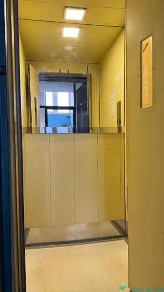 Kancelária s výhľadom na centrum Michaloviec. 16 m2 - Interiér kancelárií s výťahom a žltými stenami.