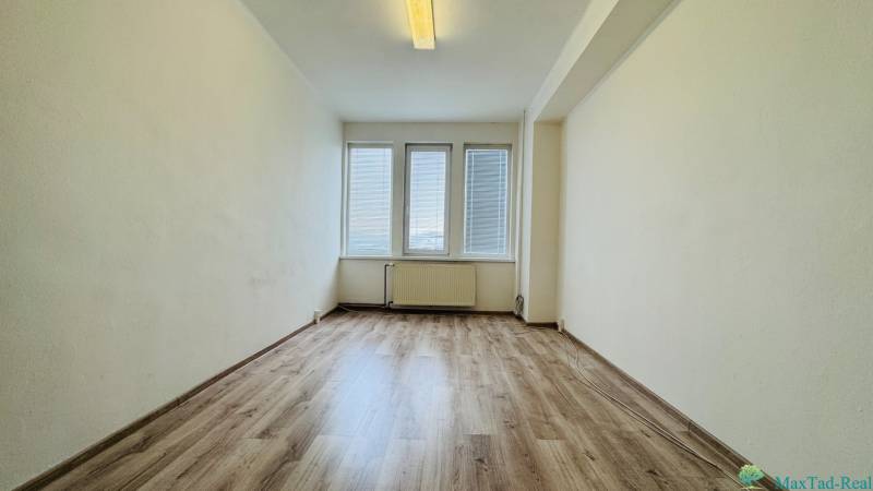 Kancelária s výhľadom na centrum Michaloviec. 16 m2 - Kancelária s veľkými oknami a podlahou s dreveným dekorom.
