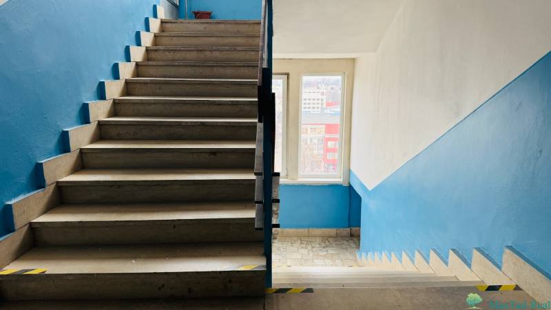 Kancelária s výhľadom na centrum Michaloviec. 16 m2 - Schodisko vo vnútorných priestoroch Kancelárie s modrými stenami a svetlými dlaždicami.