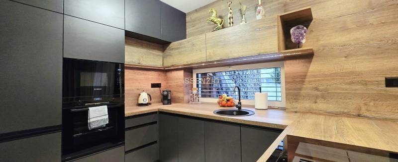 - KRÁTKODOBÝ PRENÁJOM - RODINNÝ DOM - 105 m2 - ROVINKA - Kuchyňa v rodinnom dome s tmavými skrinkami a podlahou s dreveným dekorom.