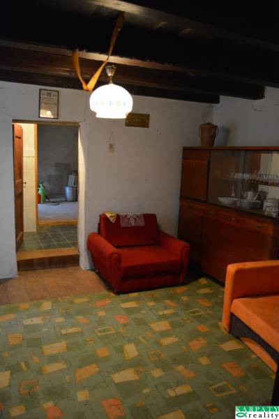 CHalúpka, na rekonštrukciu za cenu pozemku, dom Abrahám! - Obývacia izba v rodinnom dome s červeným kreslom a skrinkou s riadmi.