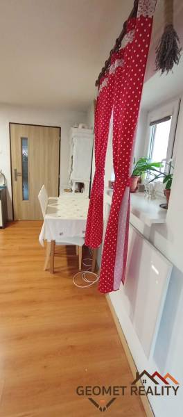 Útulný domček s dušou a moderným komfortom – Divín - Jedáleň v rodinnom dome s červeným závesom, stolom a podlahou s dreveným dekorom.