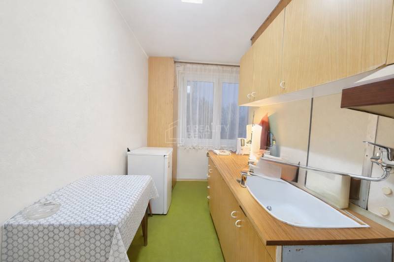 Predaj pôvodného 3+1 bytu v žiadanej lokalite v Čadci (MO) - Kuchyňa v 3-izbovom byte s jednoduchým zariadením, podlaha s dreveným dekorom.