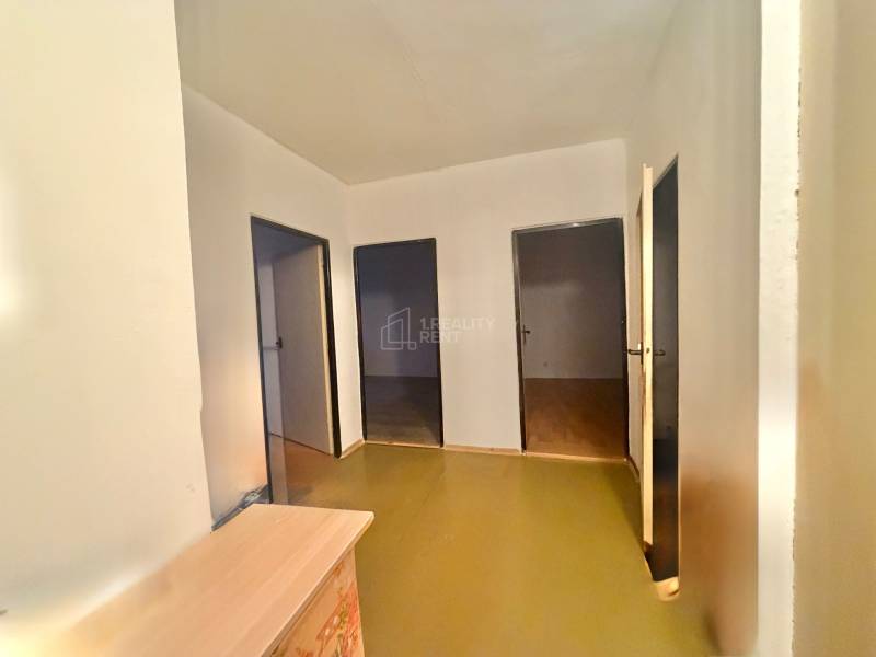 Predaj pôvodného 3+1 bytu v žiadanej lokalite v Čadci (MO) - Chodba v 3-izbovom byte so svetlými stenami a tromi dverami, podlaha s dreveným dekorom.