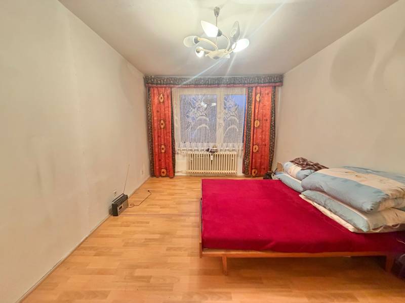 Predaj pôvodného 3+1 bytu v žiadanej lokalite v Čadci (MO) - Spálňa v 3-izbovom byte s posteľou, podlahou s dreveným dekorom a svetlom.