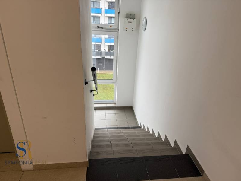 2-izbový byt novostavba s podzemným parkovaním- bez rezervačnej zálohy - Schodisko s výhľadom na okno v budove, biela stena, dlažba.