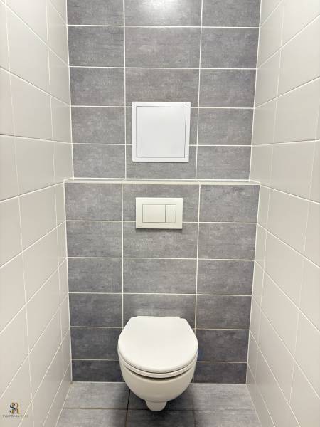 2-izbový byt novostavba s podzemným parkovaním- bez rezervačnej zálohy - Toaleta v 2-izbovom byte so sivými a bielymi obkladmi.