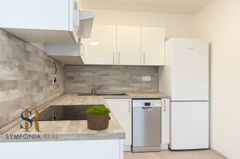 2-izbový byt novostavba s podzemným parkovaním- bez rezervačnej zálohy - Kuchyňa v 2-izbovom byte s bielymi skrinkami a podlahou s dreveným dekorom.