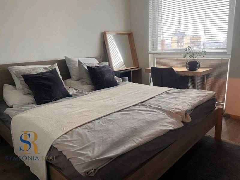 2-izbový byt v Pezinku s vlastným parkovaním - REZERVOVANÉ - Spálňa v 2-izbovom byte s posteľou, písacím stolom a podlahou s dreveným dekorom.