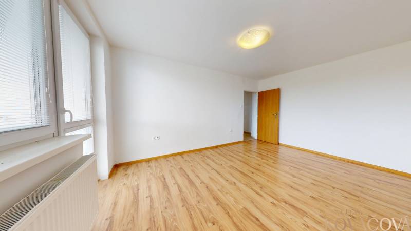 Na prenájom 2 izbový byt, Dežerice - Priestranná izba s podlahou s dreveným dekorom v 2-izbovom byte, okno s žalúziami.