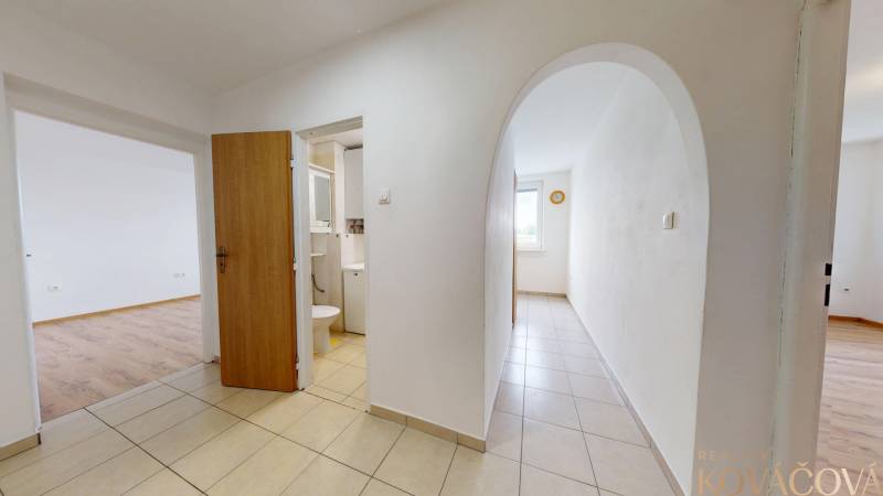 Na prenájom 2 izbový byt, Dežerice - Chodba v 2-izbovom byte s dlažbou a výhľadom na izbu s podlahou s dreveným dekorom.