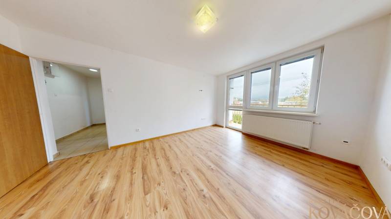 Na prenájom 2 izbový byt, Dežerice - Priestranná izba v 2-izbovom byte s podlahou s dreveným dekorom a veľkými oknami.