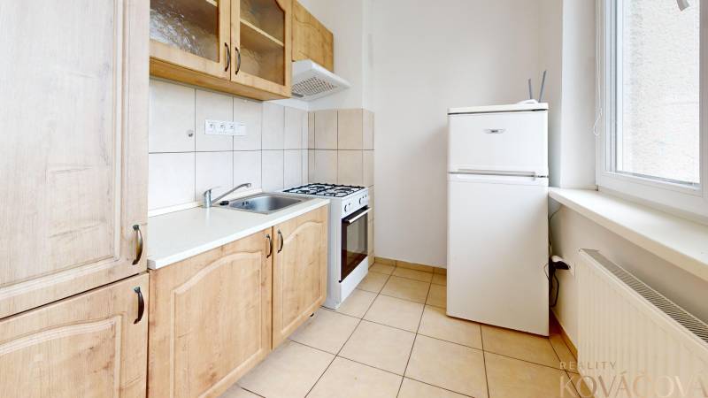 Na prenájom 2 izbový byt, Dežerice - Kuchyňa v 2-izbovom byte s kachličkami a dreveným dekorom skríň a spotrebičmi.