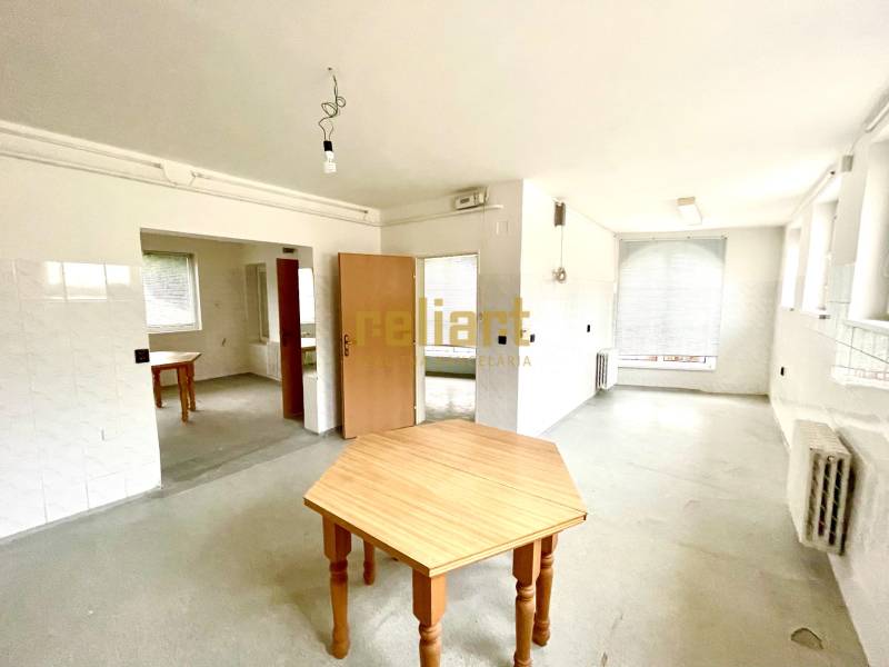 Záhorská Bystrica: Predaj domu kombinácia bývanie/podnikanie - Priestranná izba s drevenými stolmi a radiátormi v rodinnom dome.