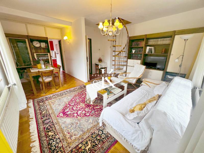 Predaj rekreačná chata s pozemkom, garážou a saunou Modra, Harmónia - Interiér chaty so špirálovým schodiskom, televíziou a stolom na podlahe s dreveným dekorom.