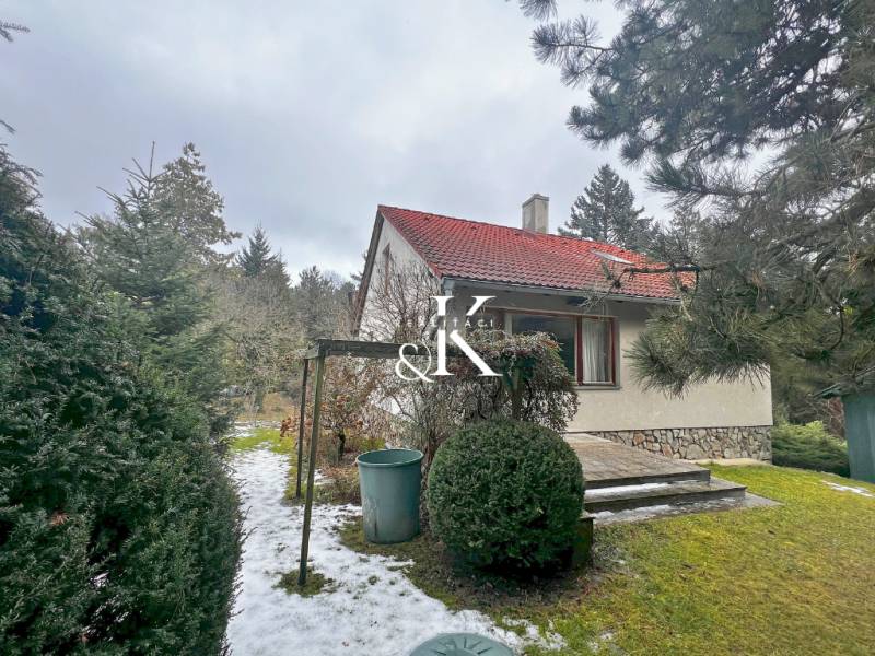 Predaj rekreačná chata s pozemkom, garážou a saunou Modra, Harmónia - Záhradná chata v Modre obklopená zeleňou a snehovou pokrývkou na chodníku.