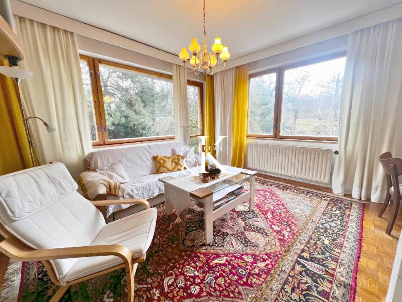 Predaj rekreačná chata s pozemkom, garážou a saunou Modra, Harmónia - Svetlá obývacia izba s podlahou s dreveným dekorom, koberec, biely nábytok, veľké okná.