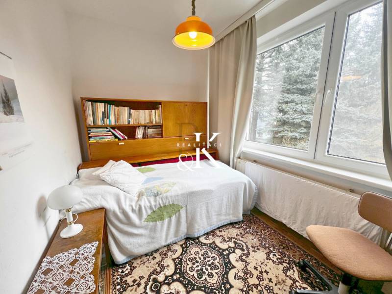 Predaj rekreačná chata s pozemkom, garážou a saunou Modra, Harmónia - Izba v chate s poličkou na knihy, posteľou a veľkým oknom.