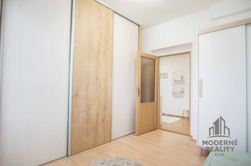 Na prenájom veľký 4-izbový byt s balkónom, garážou a záhradou, Kolta – - Interiér 4-izbového bytu s podlahou s dreveným dekorom a posuvnými skriňami.