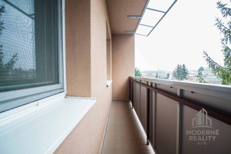 Na prenájom veľký 4-izbový byt s balkónom, garážou a záhradou, Kolta – - Balkón 4-izbového bytu v Kolte s výhľadom na zeleň a miestnu scenériu.