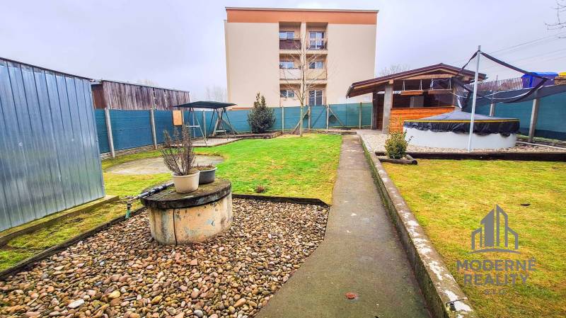 Na prenájom veľký 4-izbový byt s balkónom, garážou a záhradou, Kolta – - Záhrada pri 4-izbovom byte v Kolte so zeleňou, kôlňou a vonkajším krytým posedením.