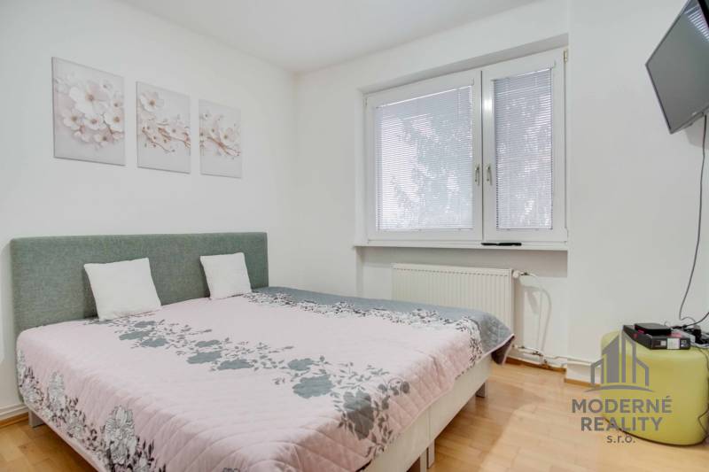 Na prenájom veľký 4-izbový byt s balkónom, garážou a záhradou, Kolta – - Spálňa v 4-izbovom byte s kvetinovými dekoráciami a televízorom na stene.