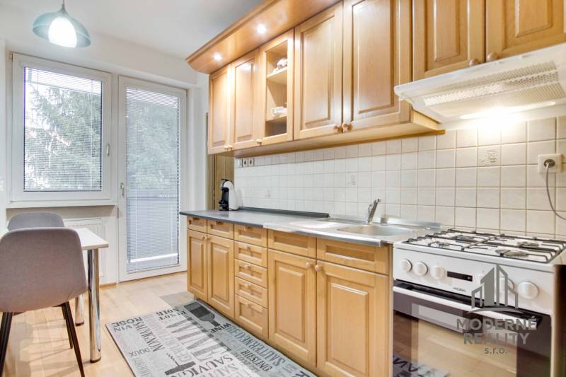 Na prenájom veľký 4-izbový byt s balkónom, garážou a záhradou, Kolta – - Kuchyňa v 4-izbovom byte s podlahou s dreveným dekorom a jedálenským kútom.