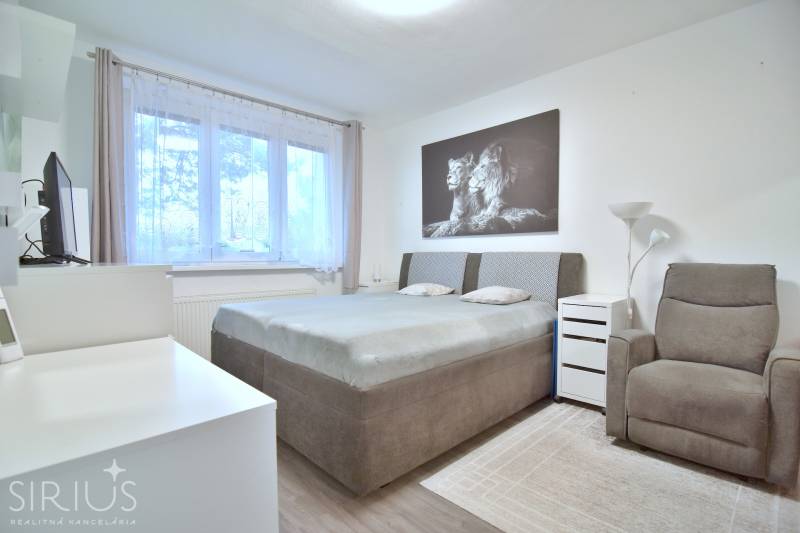 ŠTÚROVA, 3-i byt, 75 m2 – komplet rekonštrukcia, vlastné parkovanie - Spálňa s komfortnou posteľou, kreslom a obrazom v 3-izbovom byte s podlahou s dreveným dekorom.