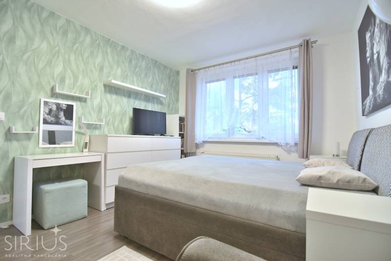 ŠTÚROVA, 3-i byt, 75 m2 – komplet rekonštrukcia, vlastné parkovanie - Spálňa v 3-izbovom byte s podlahou s dreveným dekorom a zelenou tapetou.