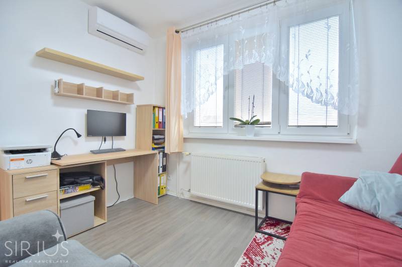 ŠTÚROVA, 3-i byt, 75 m2 – komplet rekonštrukcia, vlastné parkovanie - Izba v 3-izbovom byte s pracovným stolom, gaučom a podlahou s dreveným dekorom.