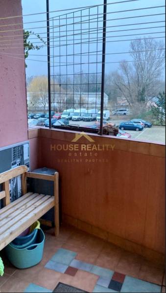 Prenájom 3 izbový byt, ulica Jána Poničana, BA IV. Devínska Nová Ves - Balkón s drevenou lavičkou, výhľad na zaparkované autá, ulica Jána Poničana, Bratislava - Devínska Nová Ves.