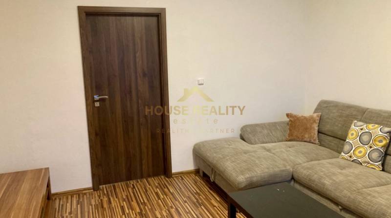 Prenájom 3 izbový byt, ulica Jána Poničana, BA IV. Devínska Nová Ves - Obývacia izba s pohovkou, drevený dekor podlahy a tmavé dvere v 3-izbovom byte.