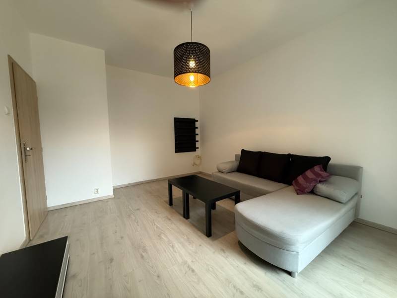 Ponúkame Vám do prenájmu 1 – izbový byt s balkónom v centre Martina - Obývacia izba s podlahou s dreveným dekorom, rozkladacou sedačkou a minimalistickým nábytkom v 1-izbovom byte.