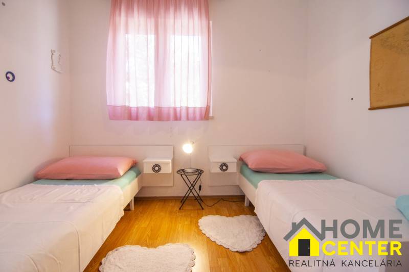 Na predaj krásny priestranný dom / 101 m²/ výhľadom na more  Čiovo - Svetlá spálňa s dvoma posteľami, ružovými závesmi a podlahou s dreveným dekorom.