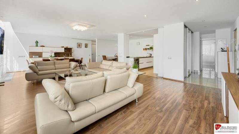 Novostavba 3 izbový byt, Palisády, 147 m2, výhľad, parkovanie, BA I - Svetlá obývačka s drevenými podlahami a béžovými pohovkami v 3-izbovom byte.