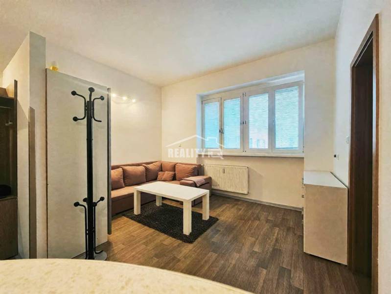 Prenájom, Garsónka, M.R.Štefánika, Centrum, Žilina - Garsónka s pohovkou, stolíkom a podlahou s dreveným dekorom.