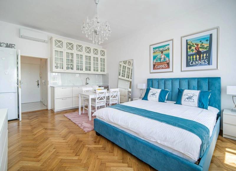 Nádherný, staromestský, 1-izb. byt v centre s výhľadom na Dunaj - 1-izbový byt s podlahou s dreveným dekorom, posteľou a bielymi kuchynskými skrinkami.