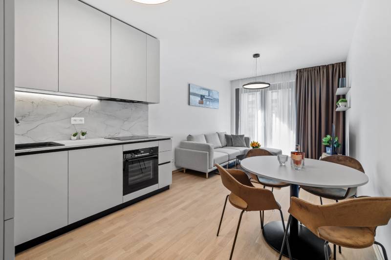 I Prenájom exkluzívneho 2-i bytu v projekte Metropolis - Kuchyňa a obývacia izba v 2-izbovom byte s podlahou s dreveným dekorom a pohodlnou sedačkou.