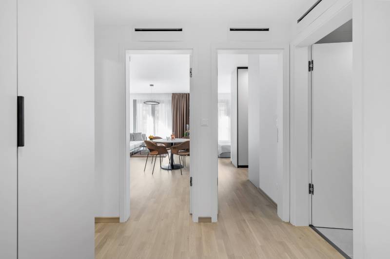 I Prenájom exkluzívneho 2-i bytu v projekte Metropolis - Interiér 2-izbového bytu s podlahou s dreveným dekorom, pohľad na obývačku a spálňu.