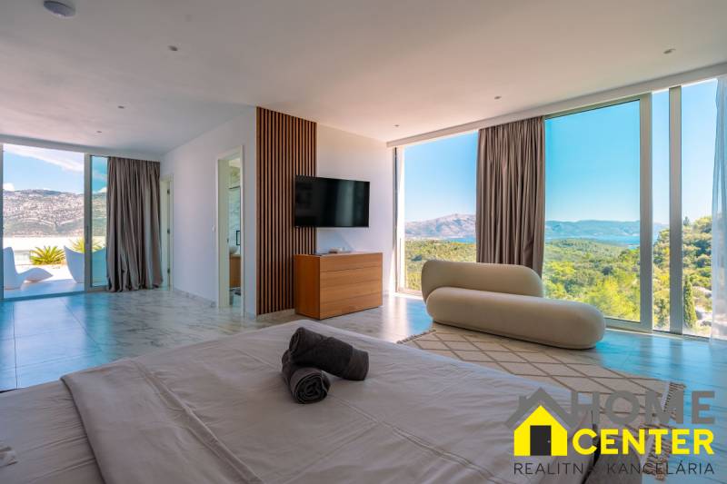NA PREDAJ Luxusná vila  /360 m²/ s infinity bazénom, mesto Korčula - Svetlá spálňa vo Vile s výhľadom cez veľké okná, podlaha s dreveným dekorom.