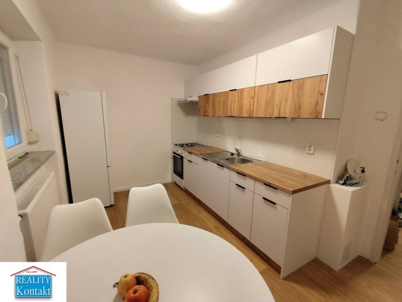 Na prenájom 2-izbový byt  Nové Zámky - Kuchyňa v 2-izbovom byte so svetlými skrinkami a podlahou s dreveným dekorom.