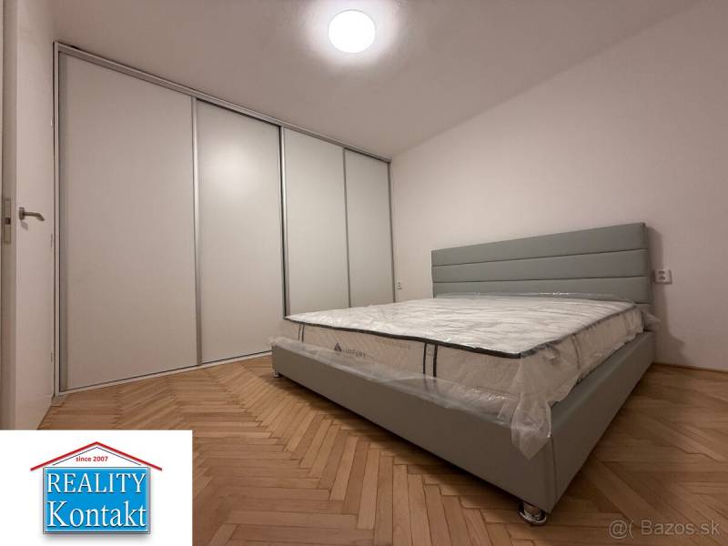 Na prenájom 2-izbový byt  Nové Zámky - Spálňa v 2-izbovom byte s podlahou s dreveným dekorom a veľkou vstavanou skriňou.