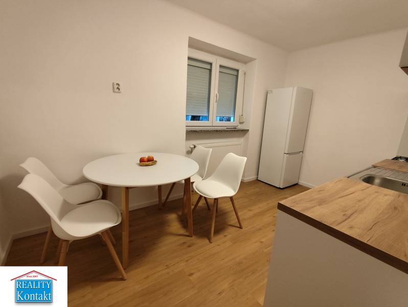 Na prenájom 2-izbový byt  Nové Zámky - Jedálenský kút s dreveným dekorom podlahy, bielym stolom a stoličkami v 2-izbovom byte.